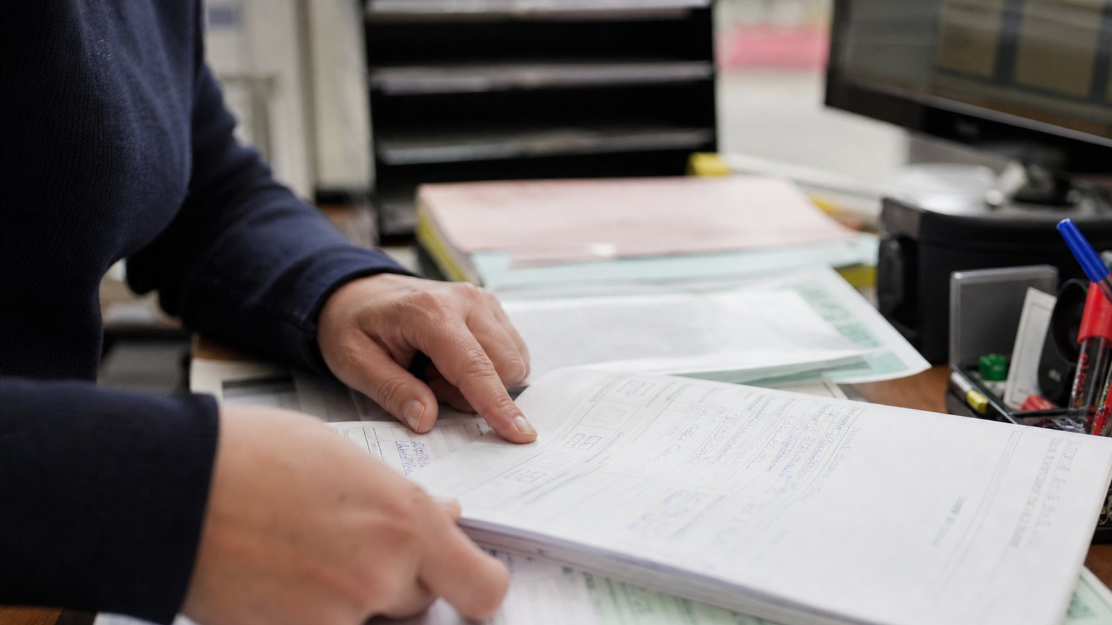 Gérant d'auto-école consultant le dossier complet d'un élève sur son poste de travail
